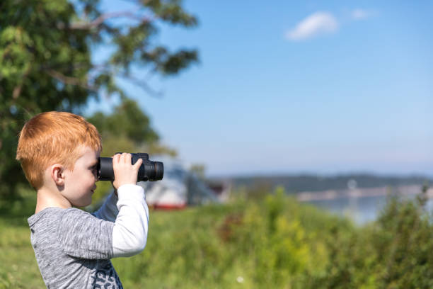istock Little Redhead Boy Whale Watching With Binoculars in Camping in Summer 1201899200