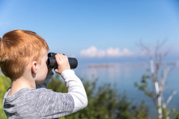 istock Little Redhead Boy Whale Watching With Binoculars in Camping in Summer 1201901444