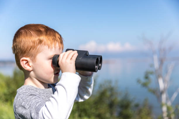 istock Little Redhead Boy Whale Watching With Binoculars in Camping in Summer 1201902376
