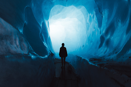 Mujer explorando el mundo de un gran glaciar dentro de la cueva de hielo en Suiza photo
