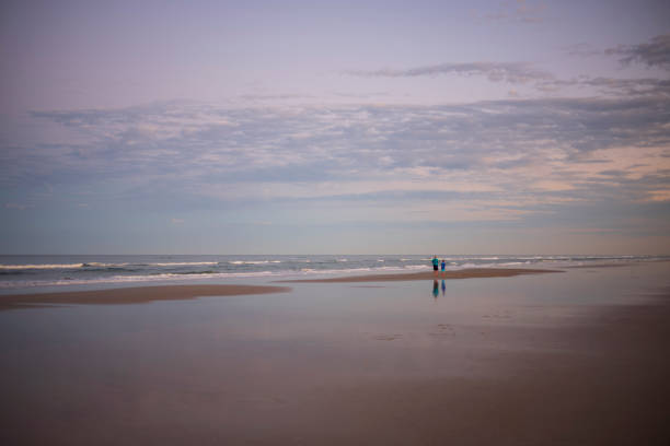 Port Orange, FLA/USA - Dec 31, 2019: A grandfather and his grandson walk the beach looking for seashells during a sunset.