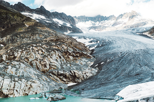 Dramatic view of Rhone melting glacier, blue glacial lake and the Swiss Alps at Furka Pass, Switzerland