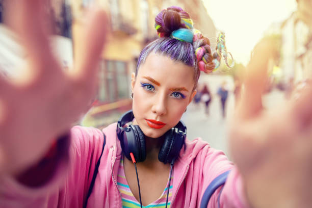 Playful cool funky hipster young girl with headphones and crazy hair taking selfie on street Cool funky young girl with headphones and crazy hair enjoy power of music taking selfie on street - hipster woman with trendy avant-garde look having fun - Music fan concept with playful carefree teen gen z stock pictures, royalty-free photos & images