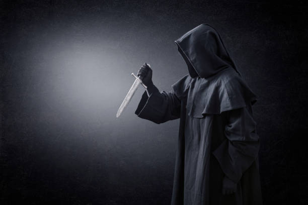 istock Hooded man with ancient knife in the dark 1201910009