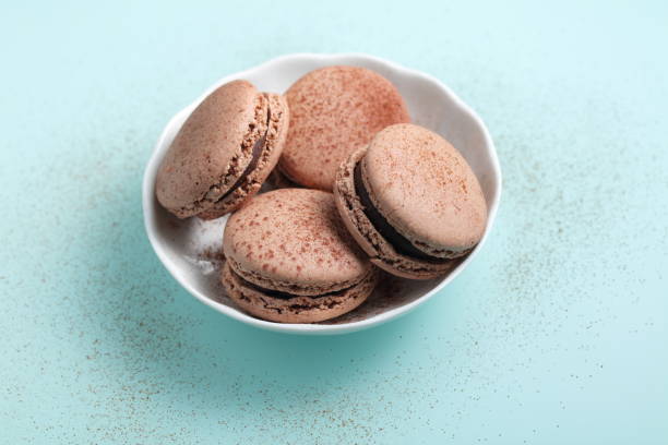 Four chocolate macarons confections against cyan background