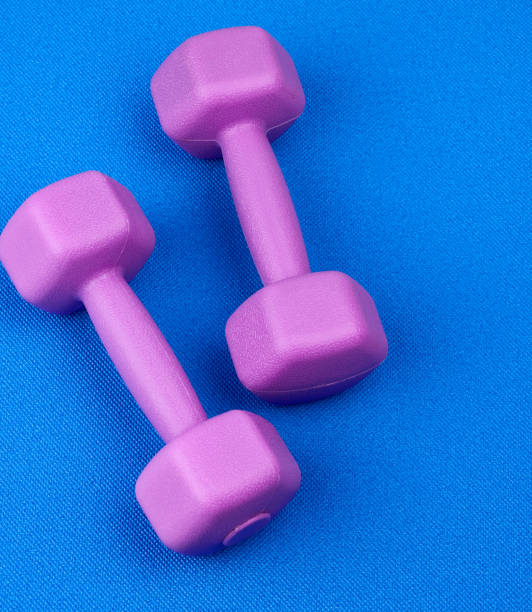 istock pair of purple plastic dumbbells on a blue neoprene mat 1201918580