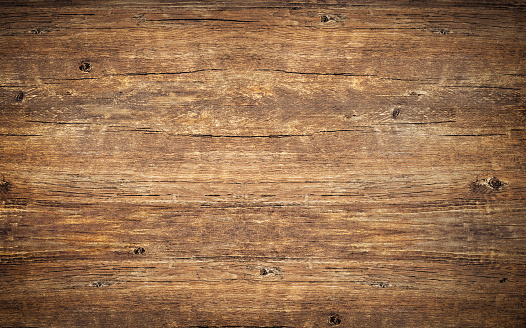 Wood texture background. Top view of vintage wooden table with cracks. Surface of old knotted wood with natural color, texture and pattern. Dark barn material. Brown rustic rough timber for backdrop.
