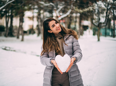 Woman Making Heart From Snow