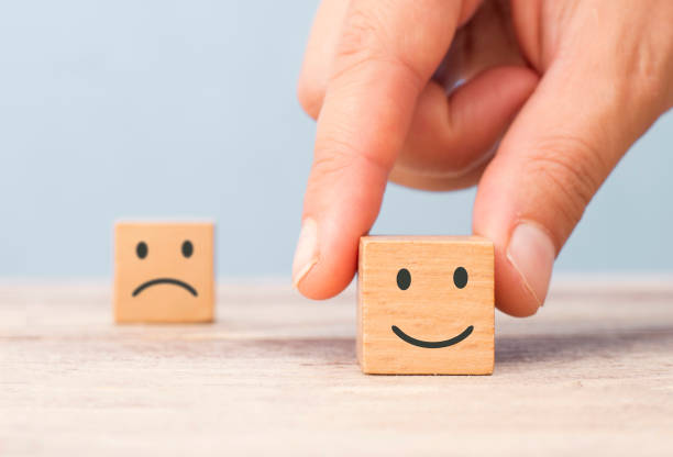 istock hand chose smiley face front of sad face.customer satisfaction concept 1201931172