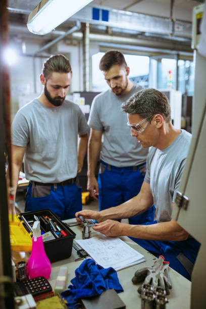 istock Senior male inspector doing quality control with manual worker looking at document and examining metal tube 1201933115