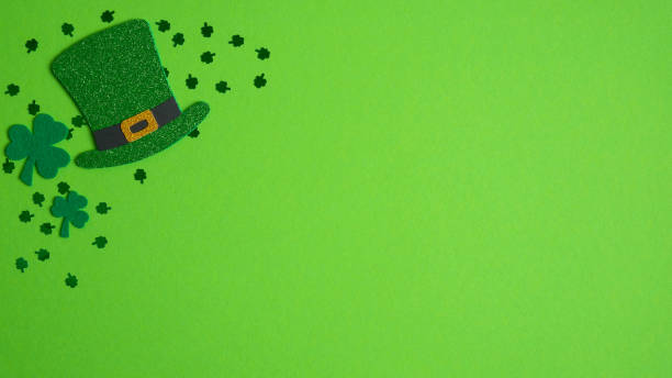 istock Happy St. Patrick's Day concept. Top view Irish elf hat, shamrock leaf clovers and confetti on green background with copy space. Saint Patricks Day greeting card template, banner mockup, poster design 1201934222