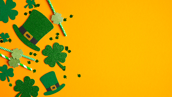 Saint Patrick's Day background with clovers shamrock symbols, Irish elf hats, confetti, party drinking straws. Happy St. Patrickâs Day concept. Greeting card, party invitation template, banner mockup