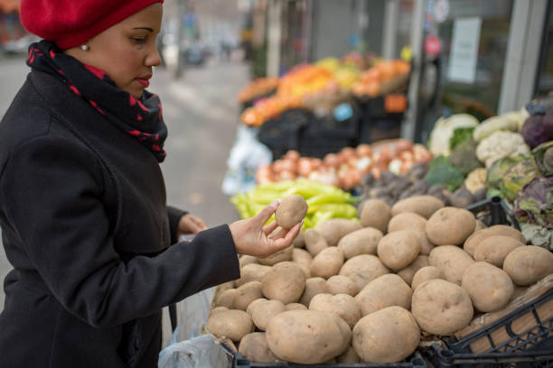 hautfarbene frau, die gemüse auf dem traditionellen markt wählt - onionskin stock-fotos und bilder