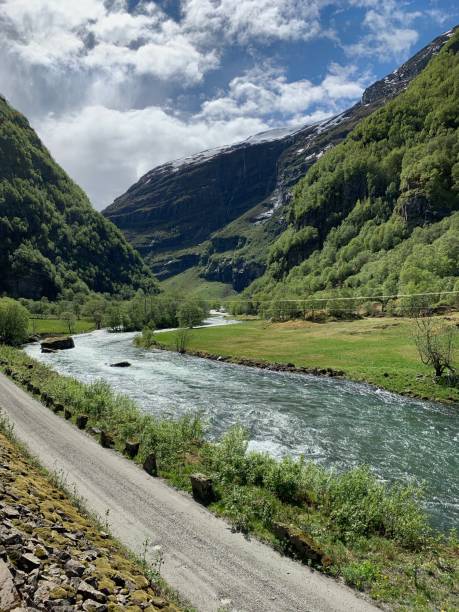 istock Dirt road along a stream at the base of a mountain range 1201940525
