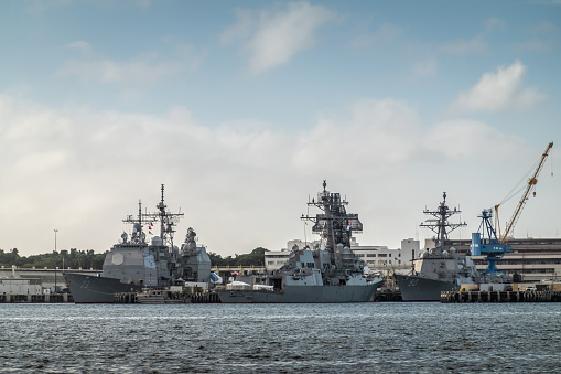 Oahu, Hawaii, USA. - January 10, 2020: Pearl Harbor. Gray USS Decatur and Chafee destroyers together with other war ships in port on dark bue gray water under light blue cloudscape.