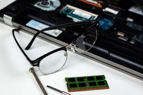 IT engineers spectacles laying on a laptop he is repairing IT engineers spectacles laying on a laptop he is repairing and upgrading the memory to installing laptop ram stock pictures, royalty-free photos & images