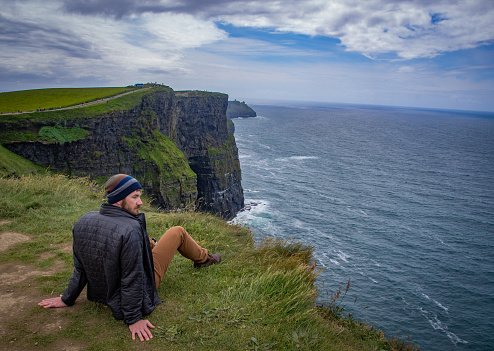 Handsome man takes in the remarkable lush cliffs and the overwhelming ocean below.
