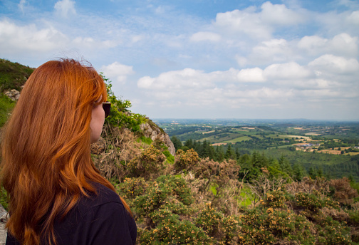 A beautiful Irish Red Headed Woman looks out over an incredible Irish view.