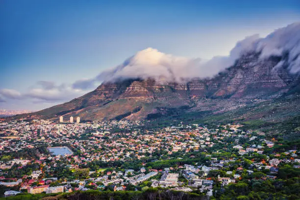 Beautiful moody twilight view from Signal Hill Road towards the city of Cape Town - Gardens, Oranjezicht and Vredehoek Districts under famous Table Mountain with stunning clouds hanging over the Table Mountains. Cape Town, South Africa, Africa