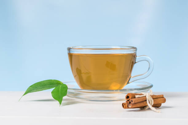 istock Cinnamon sticks and tea with green leaves on a white table on a blue background. 1202002580