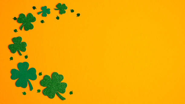 istock St Patricks Day frame border of shamrock and four-leaf clovers on orange background. Flat lay, top view. Banner design, greeting card mockup. Happy St Patrick's Day concept 1202009420