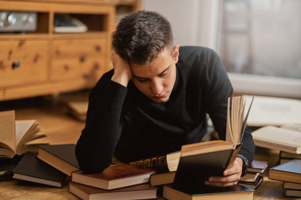 istock Young handsome student learns on the floor with books for exam 1202014430
