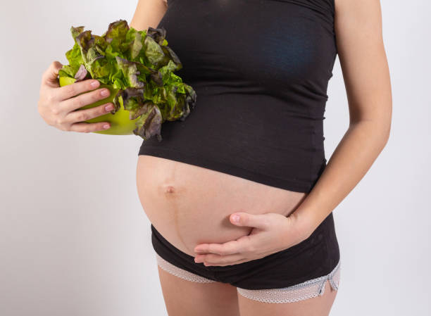 istock Pregnant woman holding fresh salad in studio 1202015624