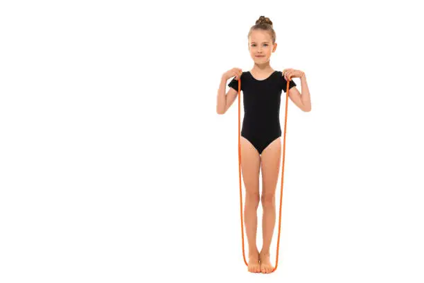 Picture of girl gymnast in black trico in full height stands on a jumping-rope.