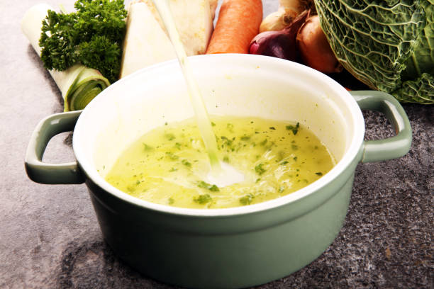 istock Broth with carrots, onions various fresh vegetables in a pot - colorful fresh clear spring soup. Rural kitchen scenery vegetarian bouillon stock 1202020780