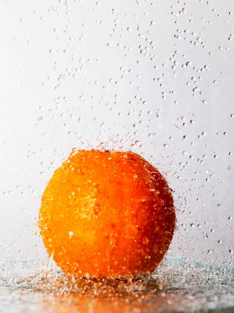 orange in spray of water, vertical image