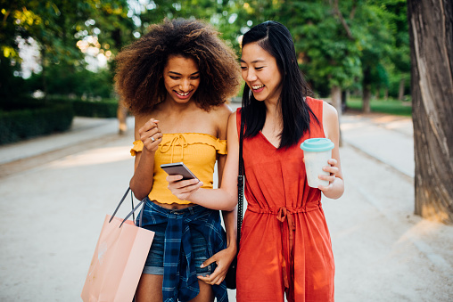 Two beautiful girls coming back from shopping and having fun online.