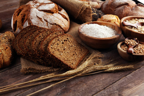 istock Assortment of baked bread and bread rolls and cutted bread on table background 1202023869