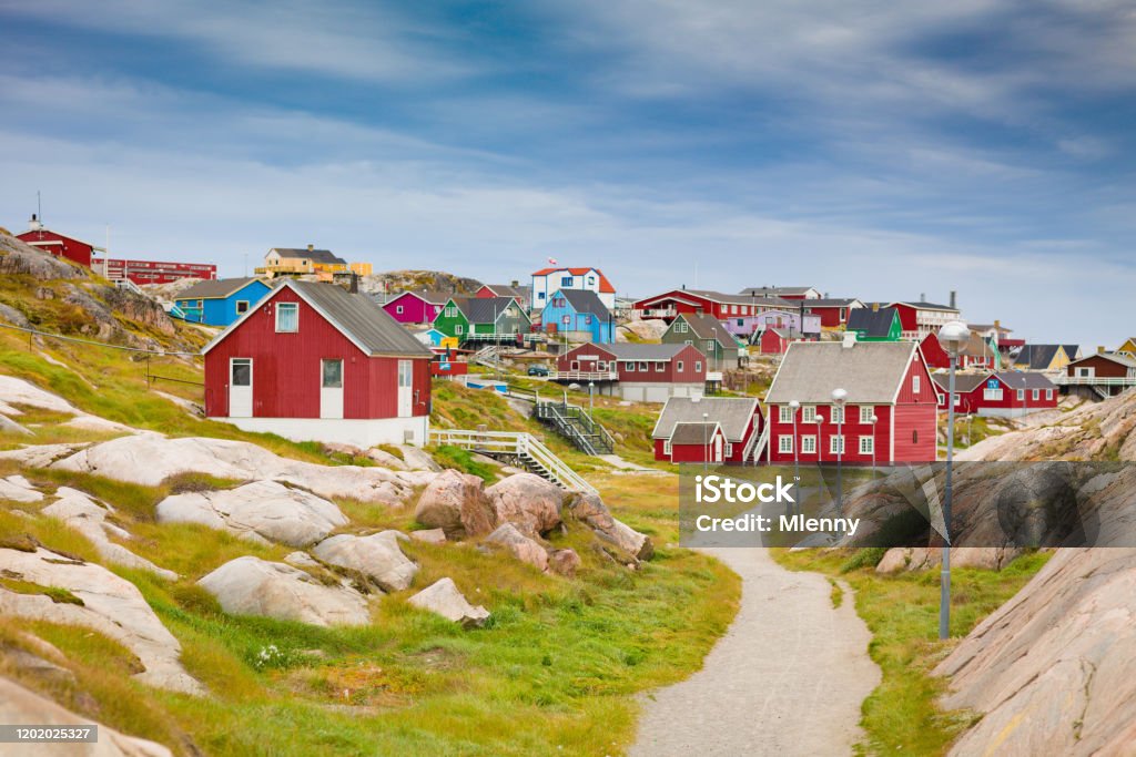 Greenland Ilulissat Colorful Town Cityscape View Ilulisaat colorful houses city - town view along sandy footpath between rocky landscape under blue summer skyscape. Ilulissat, Western Greenland, Greenland, Europe. Nuuk City Stock Photo