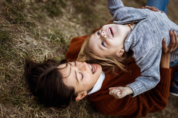 istock Playful single mother and son having fun on grass in autumn day. 1202028881