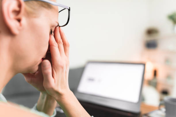 Woman feeling unwell, headache while working on a laptop.