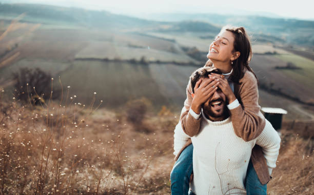 istock Young playful couple having fun while piggybacking in autumn day on a hill. 1202029399