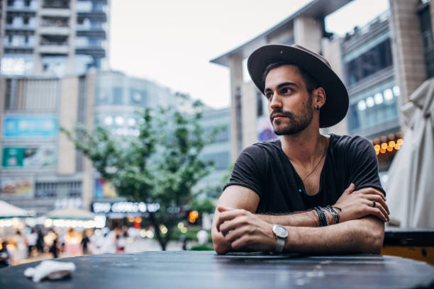 istock Handsome man with hat sitting outdoors 1202029512