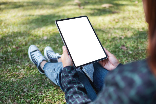 istock a woman holding and using black tablet pc with blank white desktop screen while sitting in the outdoors 1202029539