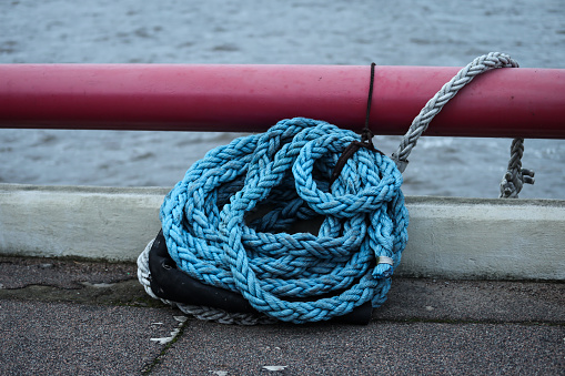 Blue strong shipping boat rope for big ship docking. Image taken on baltic sea port.
