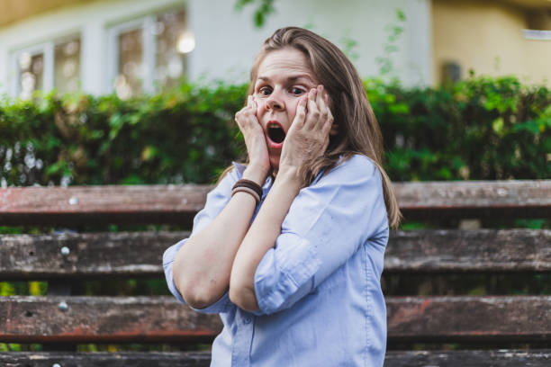 istock Scared young woman with both hands on her face outside 1202036488