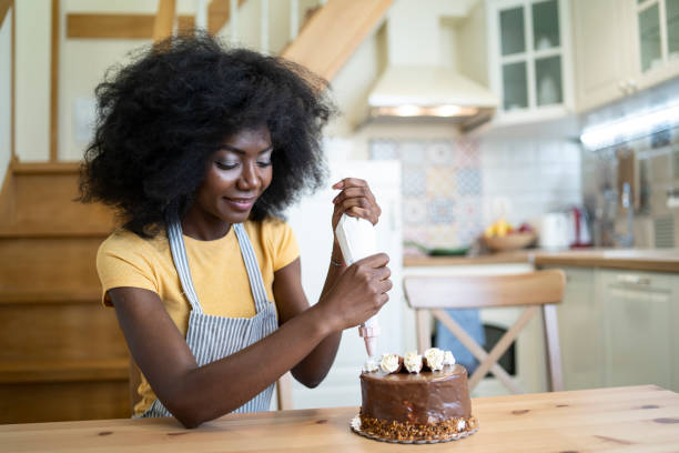 istock African woman decorating birthday cake at home, making faces 1202038138