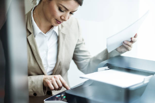 istock Young secretary pressing start button on photocopier. 1202039286