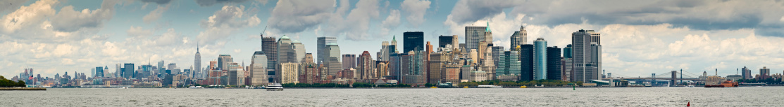 Large and detailed panoramic vista across the waters of New York Harbor, from the New Jersey shore over the Hudson River, the skyscrapers of Midtown Manhattan along the piers and promenades of Lower Manhattan, Battery Park, the iconic skyline of downtown to the historic span of the Brooklyn Bridge, the Staten Island Ferry and Brooklyn Heights. ProPhoto RGB profile for maximum color fidelity and gamut.