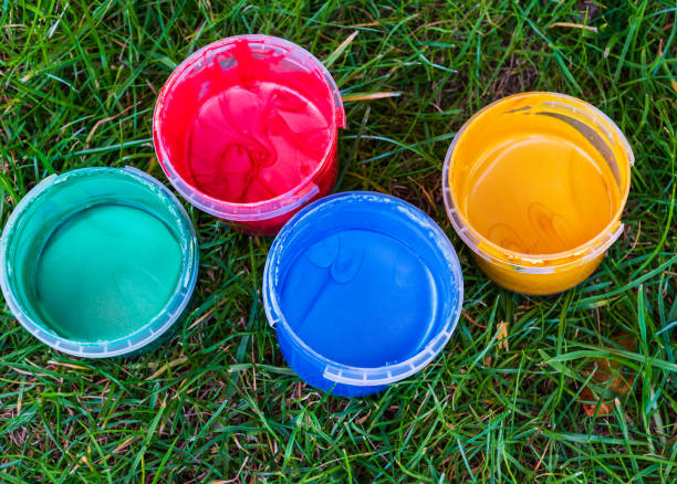 kit von vier kleinen behältern mit verschiedenen farben der fingerfarbe auf gras gefüllt. konzept von kreativität, künstlerischem hobby, spaß oder unerwartet schädlichen inhaltsstoffen in der farbe für kinder. ansicht von oben nach unten - hausgemachte fingerfarben stock-fotos und bilder