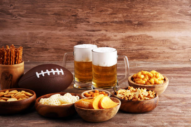 istock Chips, salty snacks, football and Beer on a table. Great for Bowl Game snack projects. 1202042426
