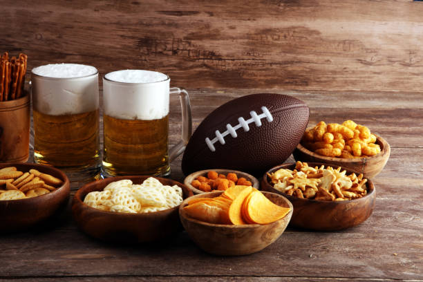 istock Chips, salty snacks, football and Beer on a table. Great for Bowl Game snack projects. 1202043077