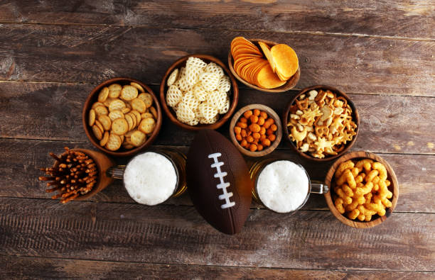 istock Chips, salty snacks, football and Beer on a table. Great for Bowl Game snack projects. 1202043109