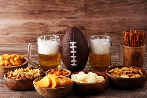 istock Chips, salty snacks, football and Beer on a table. Great for Bowl Game snack projects. 1202043148