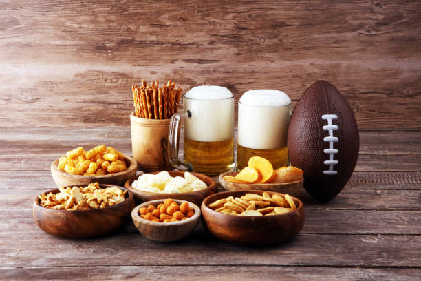 istock Chips, salty snacks, football and Beer on a table. Great for Bowl Game snack projects. 1202043289