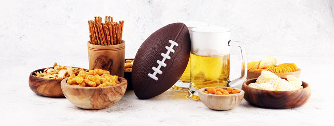 Chips, salty snacks, football and Beer on a table. Great for Bowl Game projects.